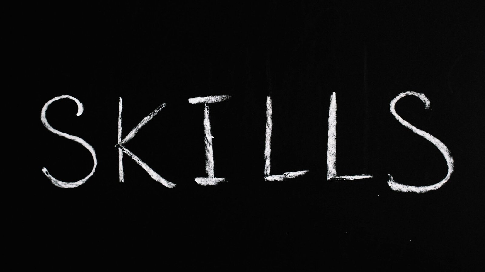 Chalk lettering of the word 'skills' on a blackboard, emphasizing learning and education.