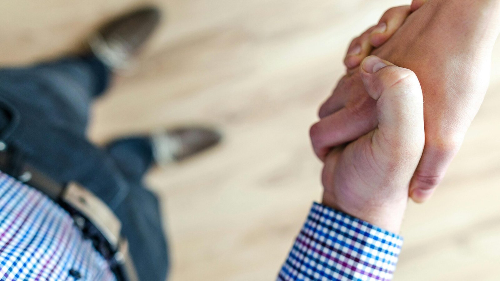 Close-up of a handshake between two people inside an office, symbolizing trust and cooperation.