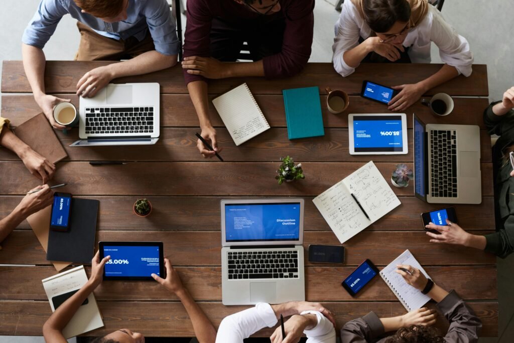 pexels-photo-3183150-3183150-1 Overhead view of a diverse team in a business meeting using laptops and tablets.