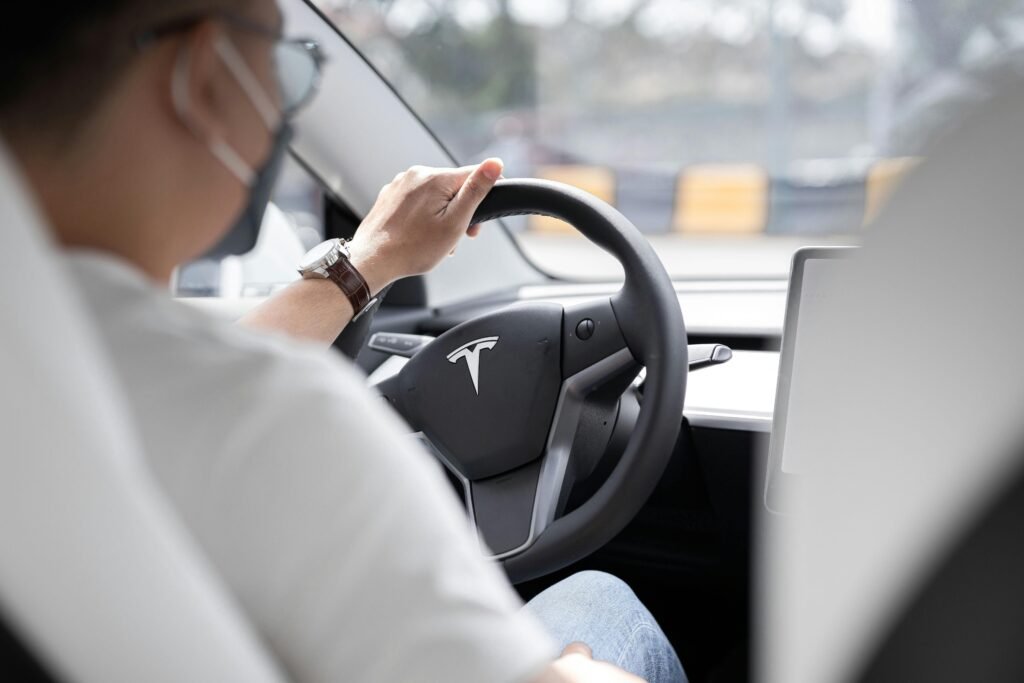 pexels-photo-10029876-10029876 Close-up photo of a person driving a Tesla, showcasing modern vehicle interior design.