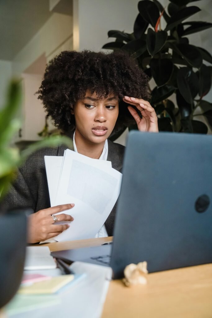 pexels-photo-12911768-12911768 Focused woman feeling stressed while working with laptop and documents at her desk.