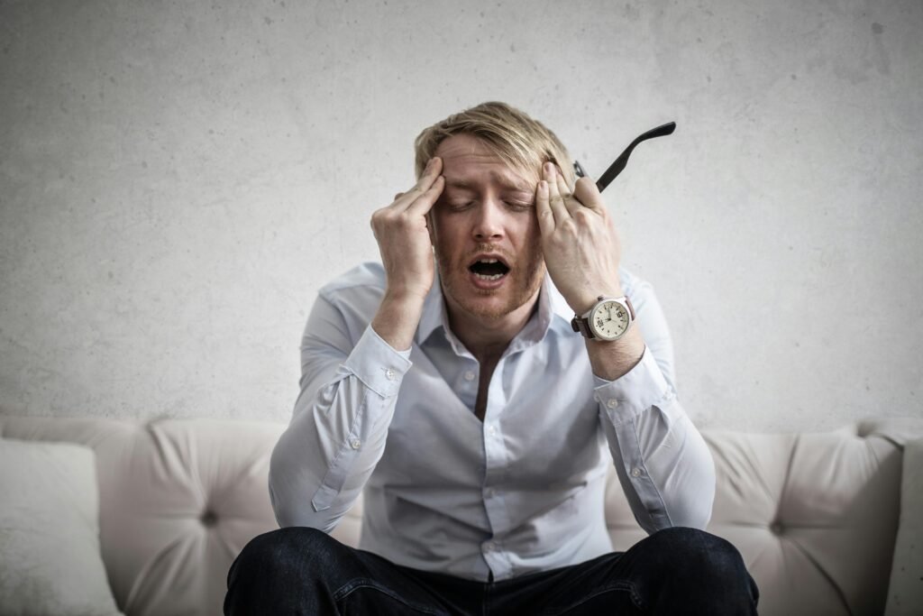 pexels-photo-3752834-3752834 Stressed man sitting on couch, feeling overwhelmed and frustrated, expressing mental strain.
