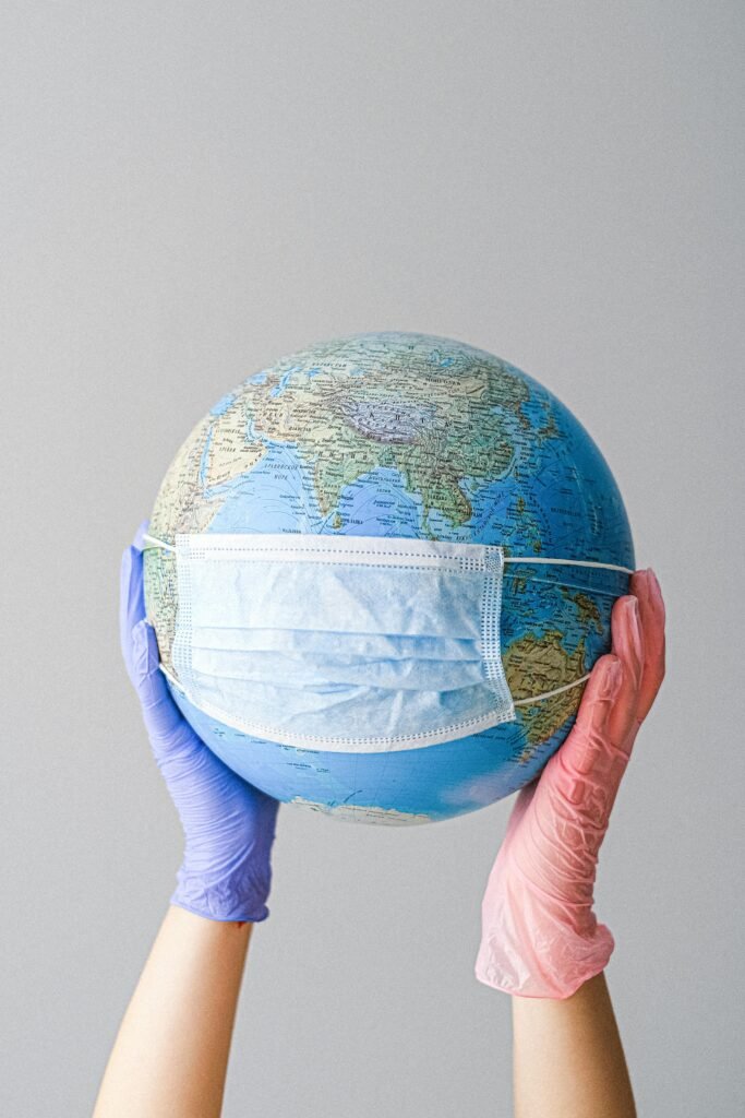 pexels-photo-4167544-4167544 Hands in gloves holding a globe with a mask, symbolizing global health and pandemic protection.