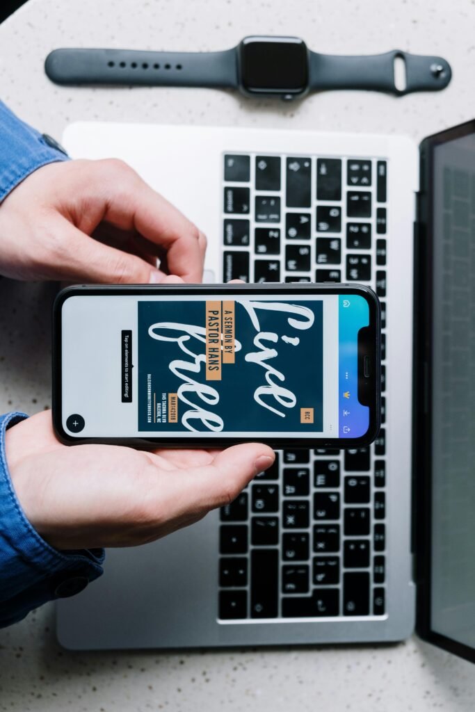 pexels-photo-5054348-5054348 Overhead view of a smartphone displaying 'Live Free' on a laptop keyboard, beside a smartwatch.