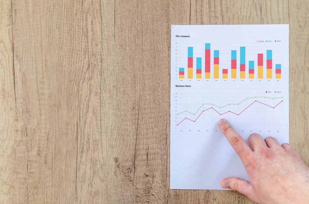 pexels-photo-590041-590041 Hand analyzing business graphs on a wooden desk, focusing on data results and growth analysis.