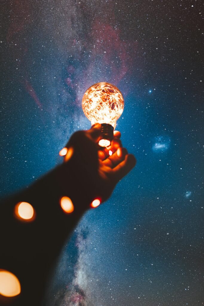 pexels-photo-1830252-1830252 A hand holds a glowing bulb into the Milky Way night sky, creating a magical cosmic connection.